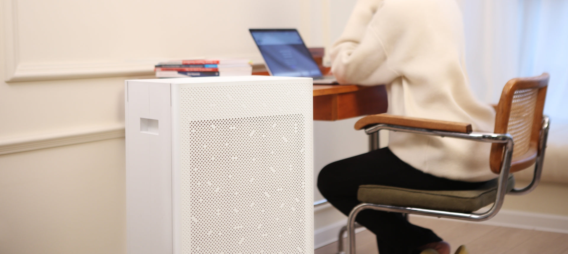 Smart Air SA600 Air Purifier with woman working on a laptop on a desk in the background