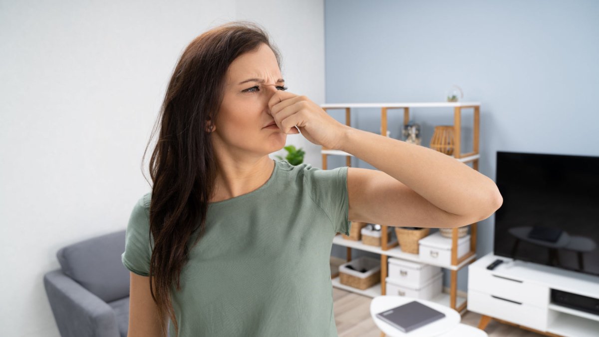 Woman in lounge holding nose due to smell