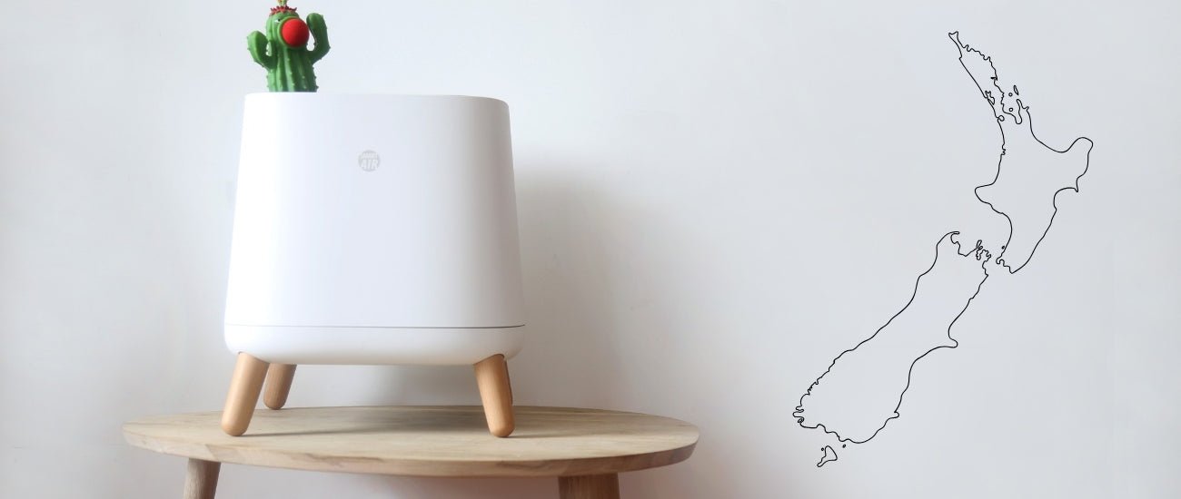 Smart Air Sqair Air Purifier on a table with white wall behind and outline of New Zealand on the side