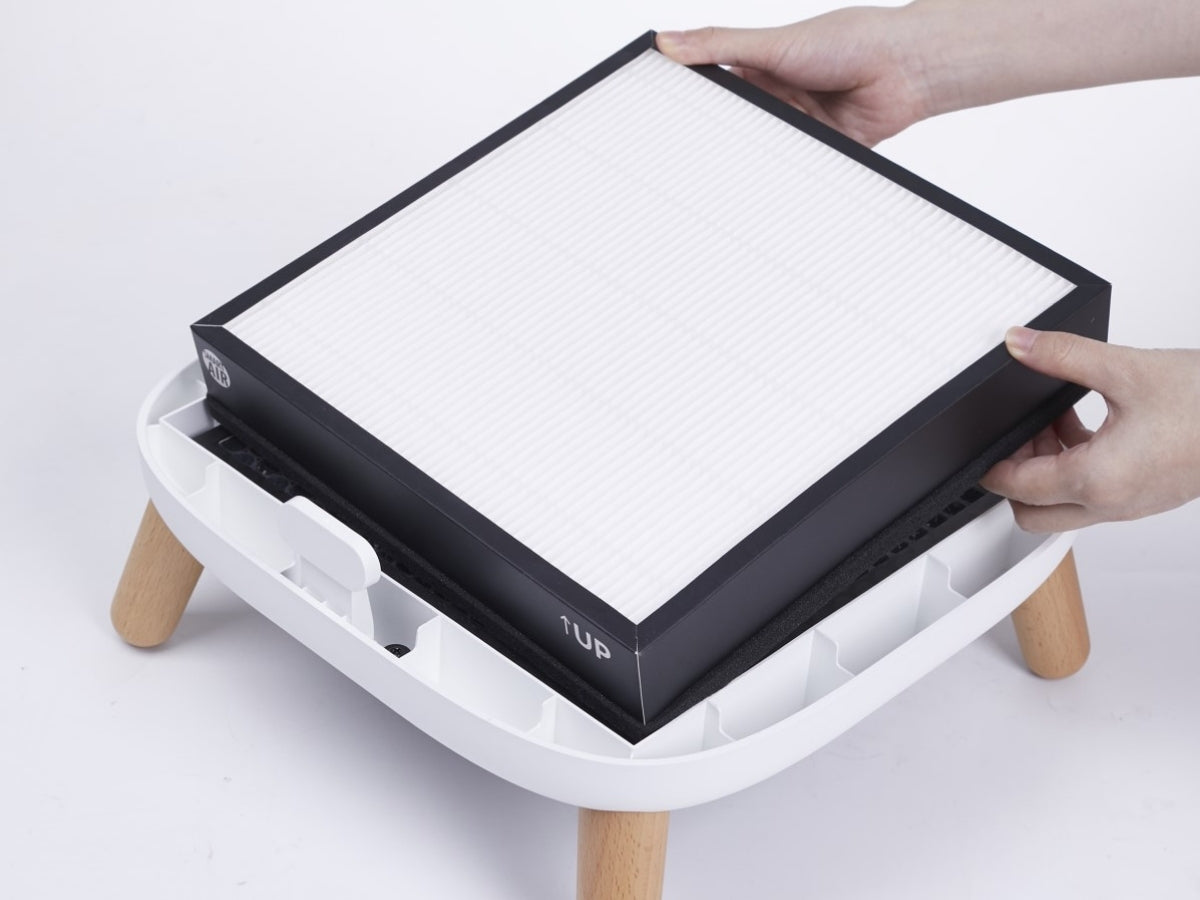 Person placing a replacement HEPA filter on Smart Air Sqair air purifier with light grey background