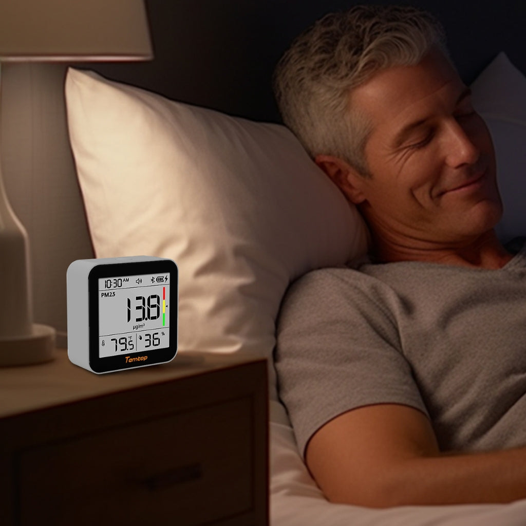 Man lying in bed with Temtop M10+ displaying PM2.5 readings next to him.