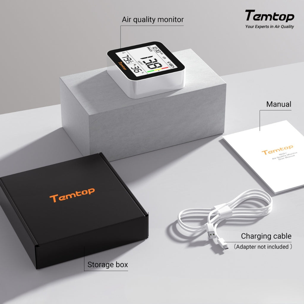 Temtop M10+ air quality monitor with packaging, manual, and charging cable on a grey surface