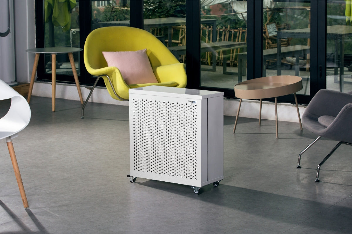 Smart Air blast mini air purifier on a grey floor with modern chairs in the background