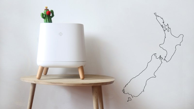Outline of NZ on a wall with Smart Air Sqair air purifier on a table next to it