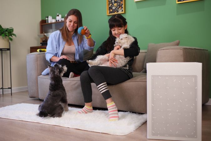 Woman and child with dogs in a living room next to a Smart Air SA600 air purifier.