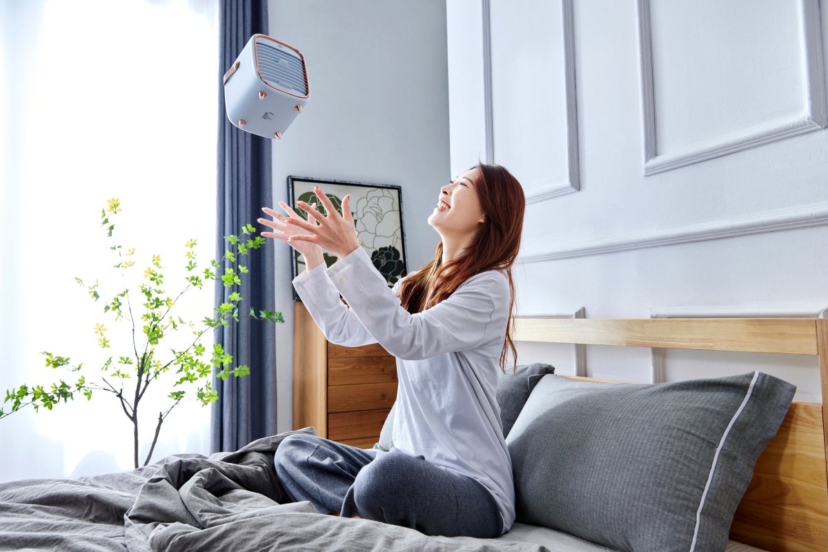 Woman throwing her Smart Air QT3 portable air purifier in the air while in bed