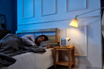 Woman sleeping with her Smart Air QT3 portable air purifier placed on bedside table