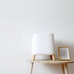 Smart Air Sqair air purifier on wooden table next to 'HOME' picture with white wall behind it