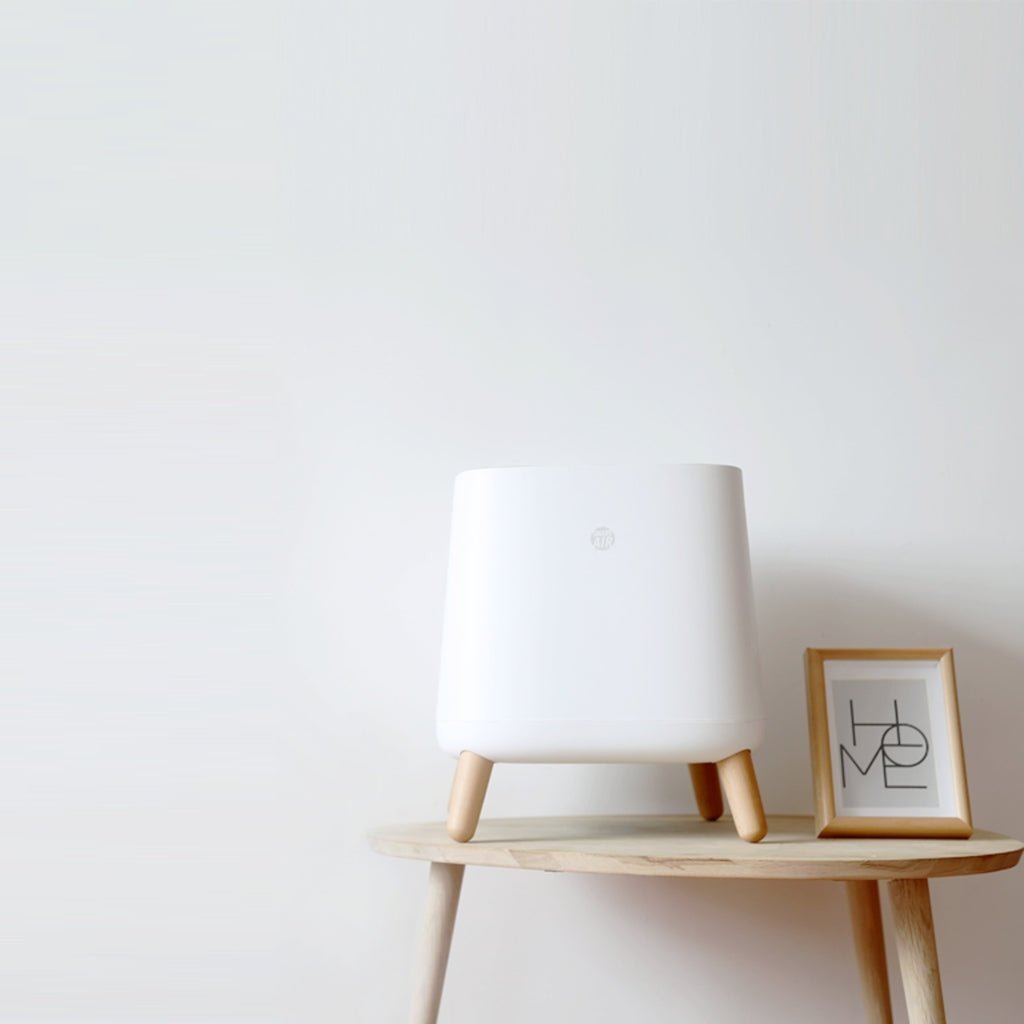 Smart Air Sqair air purifier on wooden table next to 'HOME' picture with white wall behind it